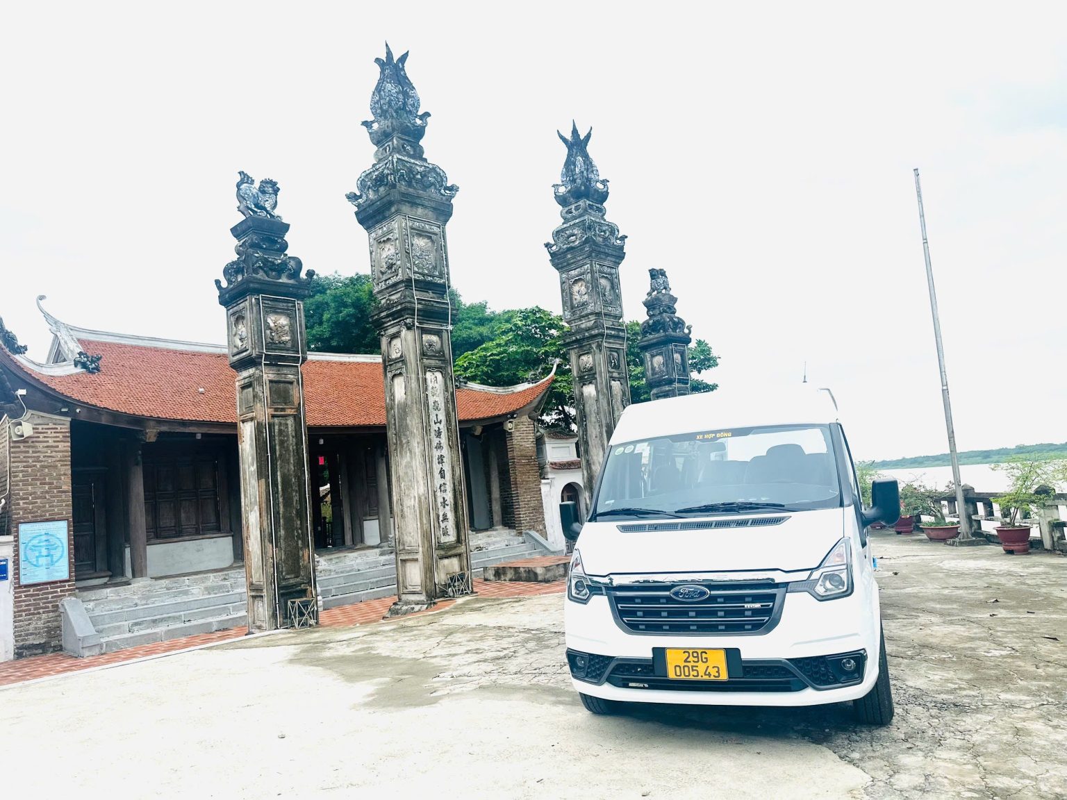 Xe Ford Transit màu trắng đỗ trước cổng đền truyền thống ở miền Bắc Việt Nam